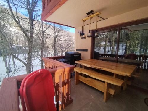 eine abgeschirmte Veranda mit einem Holztisch und einer Bank in der Unterkunft Apartamento cercano a Termas de Chillán in Las Trancas