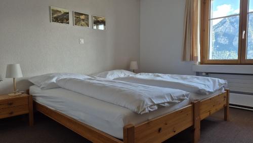 a bedroom with a bed with white sheets and a window at Garni Sternen in Obstalden