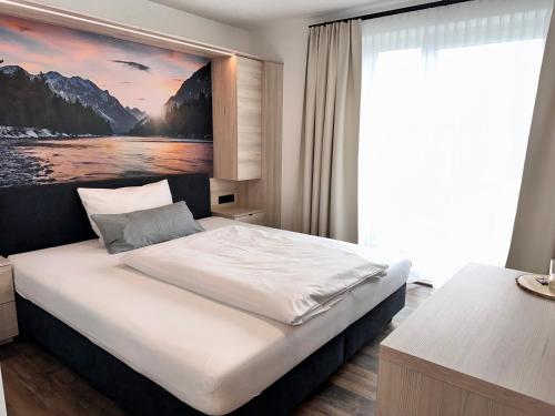 a bedroom with a bed with a painting on the wall at Hotel Lainbach in Wängle in Reutte