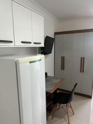 a kitchen with a refrigerator and a table and a chair at Studio Cyar 45 - Ar-condicionado e Conforto in Taubaté