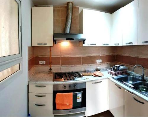 a kitchen with white cabinets and a stove and a sink at Location Estivale Hammamet in Bin Rhilouf