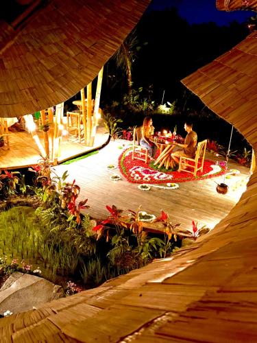two people sitting in chairs around a table at night at Green Lander Ubud in Ubud