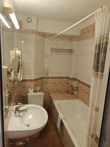 a bathroom with a tub and a toilet and a sink at Noviz Hotel in Plovdiv