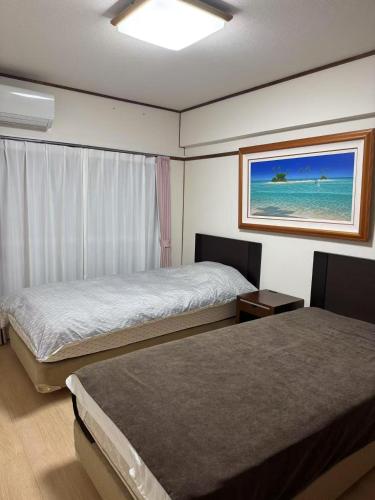 a bedroom with two beds and a picture of the ocean at 長期滞在 HYGGE HOUSE 駐車無料 JR北柏駅徒歩2分 フルキッチン 洗濯乾燥機 高速Wi-Fi アメニティ完備 上野30分 成田or羽田空港60分 in Kashiwa