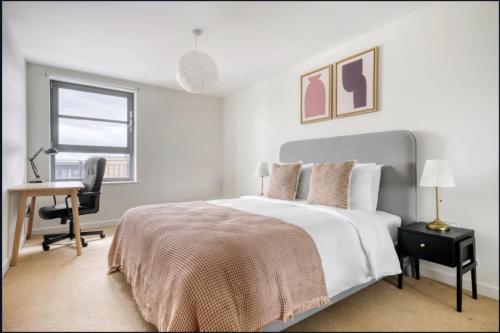 a white bedroom with a bed and a desk at Spacious 1-bed Apartment Limehouse Marina in London