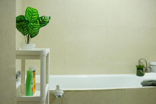 La salle de bains est pourvue d'une baignoire blanche et d'une plante verte. dans l'établissement Élégant appartement au cœur de Rabat, à Rabat