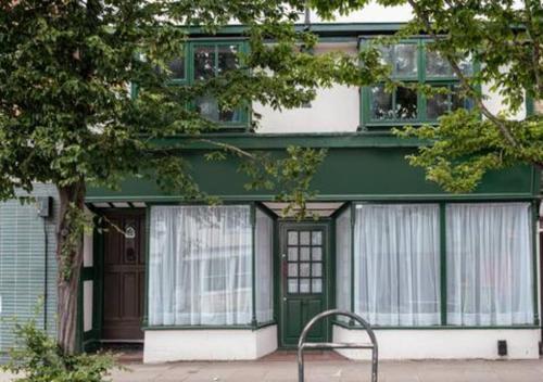 a green and white building with a bench in front of it at Ye Old Shop Milton by Sheppey Stays in Kent