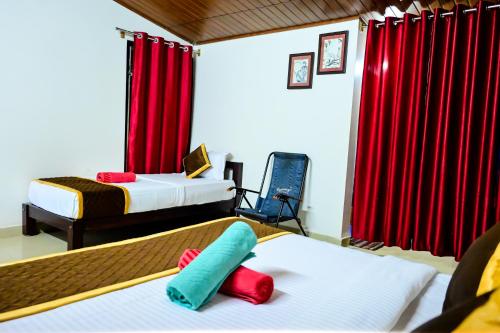 a hotel room with two beds and red curtains at Kumbles Misty Mount in Attigundi