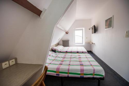 two beds in a attic room with a window at La Chaumière in Nantes