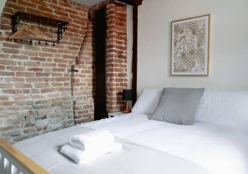 a bed in a room with a brick wall at Ye Old Shop Milton by Sheppey Stays in Kent