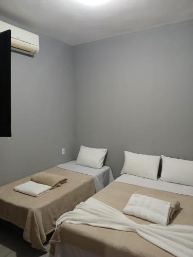 two beds in a room with white walls at Pousada Milagres de Maria in Aparecida