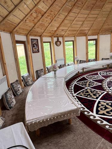 a large room with a table and a rug at Altygat Lodge Barskoon in Barskoon