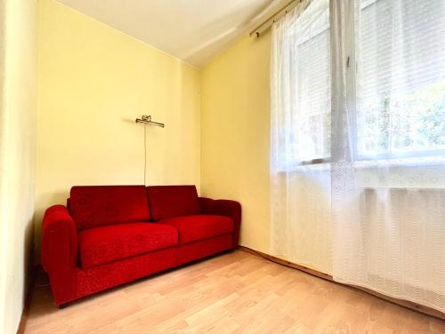 a red couch in a room with a window at Muskatli in Zalakaros