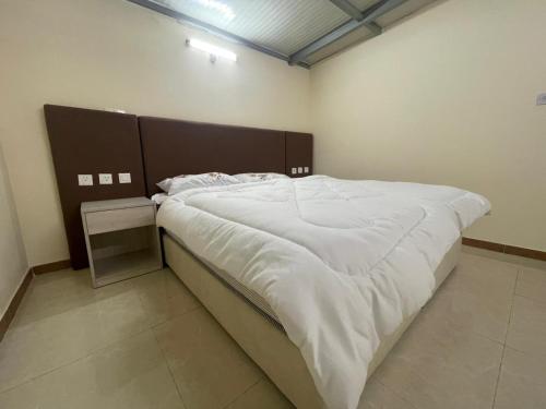a bedroom with a large bed with white sheets at Lush 25 Acre Farm Stay I, Play & Serenity in Al Ḩamrānīyah