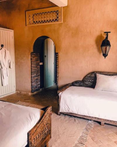 a bedroom with two beds and an arched doorway at Le Palais Mandarine in Taroudant