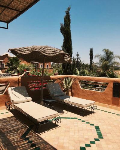 two lounge chairs and an umbrella on a patio at Le Palais Mandarine in Taroudant