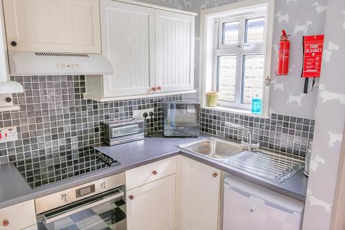 Una cocina con gabinetes blancos y un fregadero. en Finest Retreats - Evergreen Manor, en Middleton in Teesdale