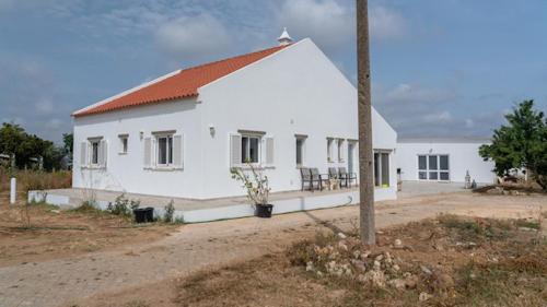 a white building with a red roof on a dirt road at Quinta Madrugada Burgau in Luz