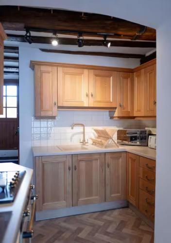 a kitchen with wooden cabinets and a sink at Ye Old Shop Milton by Sheppey Stays in Kent