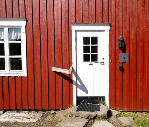 a red building with a white door and two windows at Statsbuene i Kabelvåg in Kabelvåg