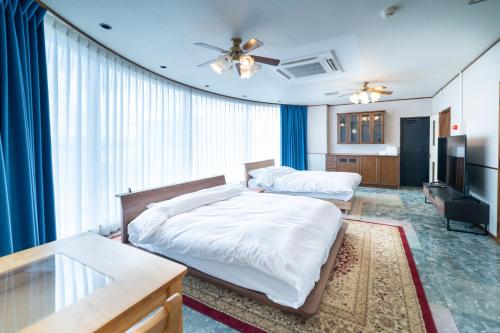 a bedroom with two beds and a television at 最大20名宿泊可能 大型テレビでスポーツ観戦 グループ旅行に最適 KOEI HOUSE in AWASE in Okinawa City
