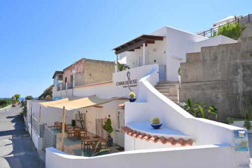 a white building with tables and umbrellas on a street at Chiaia Di Rose Rooms & Apartment in Ischia