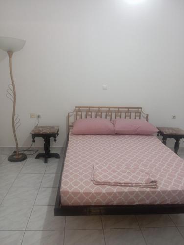 a bedroom with a bed with pink pillows and a lamp at Ευρυχωρο ισόγειο διαμέρισμα in Moláoi