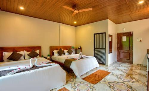 a bedroom with two beds and a ceiling fan at La Roca Inn in Assagao