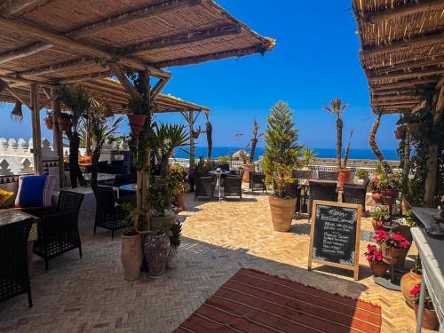 a patio with tables and chairs and plants and the ocean at Riad Al-Qurtubi in Tangier