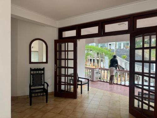 a person standing on a balcony looking out the door at Minthula Hotel & Restaurant in Kandy