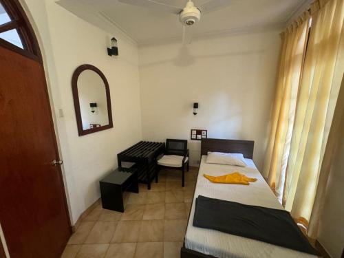 a room with two beds and a chair and a mirror at Minthula Hotel & Restaurant in Kandy