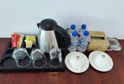 a tea kettle and glasses on a tray with water bottles at SoonNoeng Resort in Koh Rong Sanloem