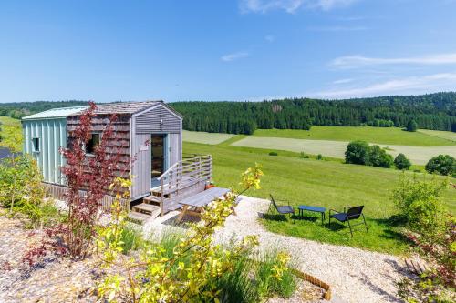 un petit hangar dans un champ avec un banc et une chaise dans l'établissement Tiny house Vata, à Les Alliés