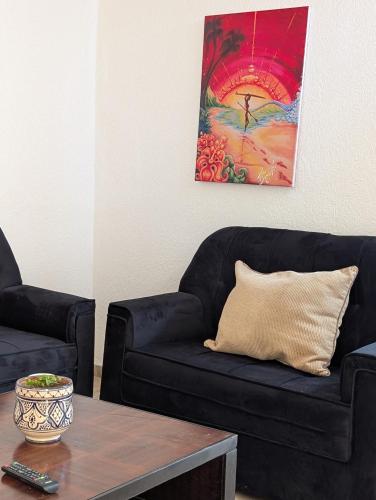 a living room with a black couch and a table at Beach House - Tamraght, Aourir in Aourir