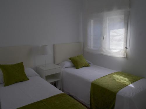 two beds in a small room with a window at Chancelas b in Combarro