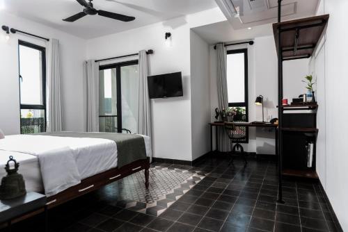 a bedroom with a bed and a tv and windows at Aquarius Hotel and Urban Resort in Phnom Penh