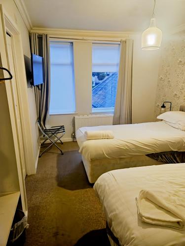 a hotel room with three beds and a television at The Coach House in Otterburn