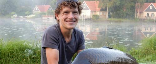 a young man sitting in front of a body of water at Timmerholt Vakantiehuis 177 in Westerbork
