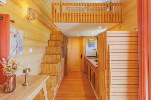 un couloir d'une cabane avec des murs en bois et une cuisine dans l'établissement Tiny house Pitta, à Les Alliés