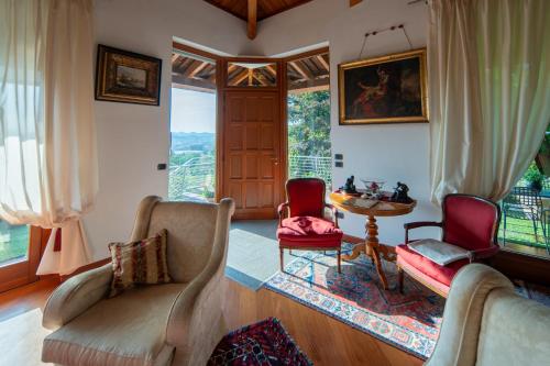 sala de estar con 2 sillas, mesa y ventanas en Villa DAutore, en Alba
