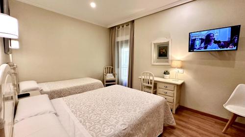 a hotel room with two beds and a flat screen tv at Hostal Toledo in Toledo