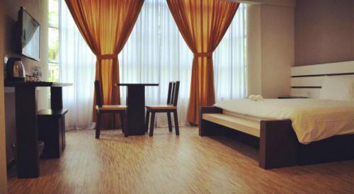 a bedroom with a bed and a table and chairs at Grand Kapar Hotel Kuala Selangor in Kuala Selangor