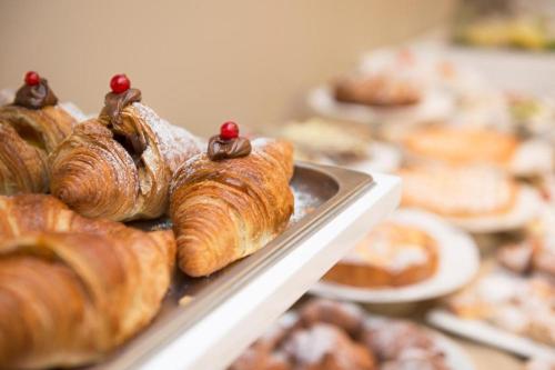 a bunch of croissants and other pastries on a tray at Hotel Fiamma & SPA Cesenatico in Cesenatico
