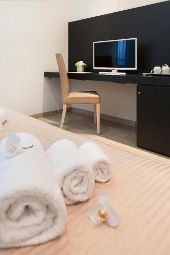 a hotel room with towels on a bed with a desk at Hotel Fiamma & SPA Cesenatico in Cesenatico
