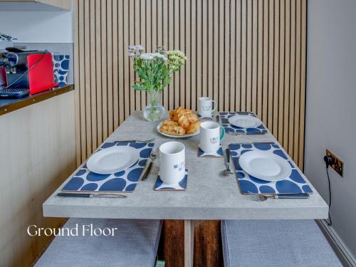 a table with blue and white plates and a vase of flowers at Inviting 2-Bed apartments - Perfect for Contractors & Business Travellers Parking - Wi-Fi - Netflix in Retford