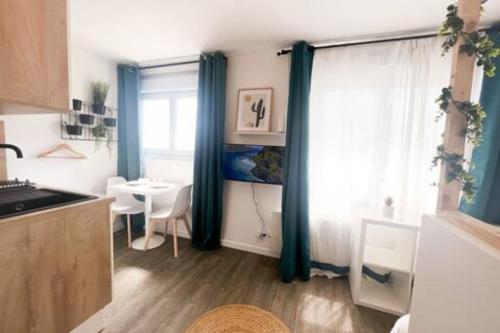 cocina con cortinas azules, mesa y ventana en Les studios de l'Albatros, en Saint-Nazaire