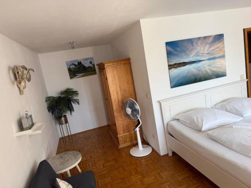 a bedroom with a bed and a desk and a fan at Hotel ChiemseePanorama in Gstadt am Chiemsee