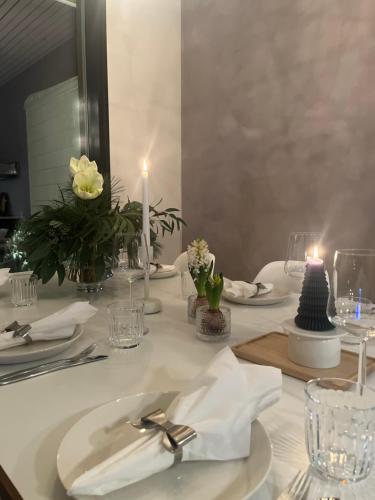 a white table with white plates and candles on it at Arctic Riverside Villa in Rovaniemi