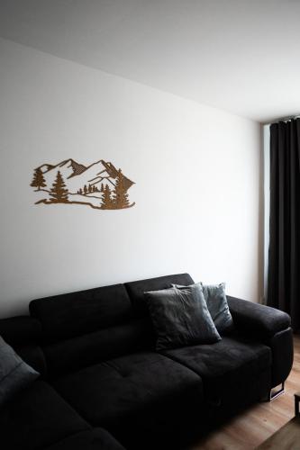 a black couch in a living room with a wall at Apartmán BeVi in Loučná nad Desnou
