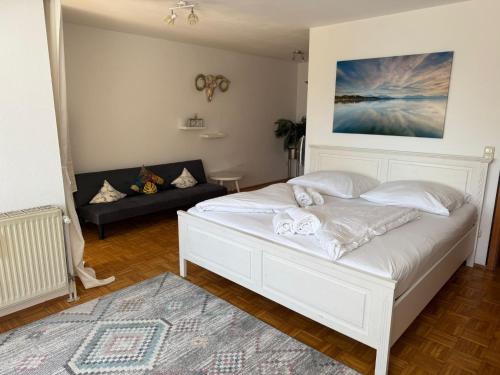 a bedroom with a white bed and a couch at Hotel ChiemseePanorama in Gstadt am Chiemsee